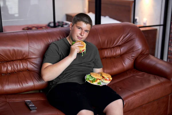 El chico está comiendo en exceso. Niño gordo, adicción a los alimentos y problemas de comportamiento. — Foto de Stock