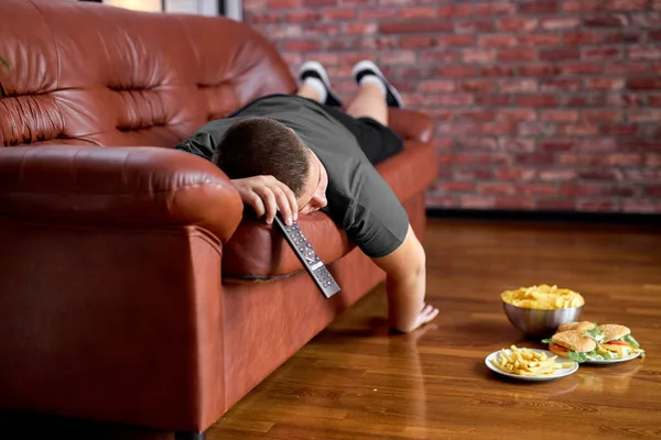 Pigro grasso ragazzo dormire su divano in soggiorno, giovane caucasico teen boy addormentarsi — Foto Stock