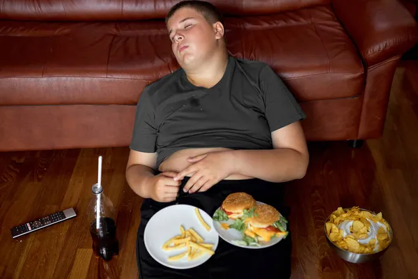 Mangiare troppo ragazzo dormire sul pavimento in soggiorno, giovane ragazzo adolescente caucasico addormentarsi — Foto Stock