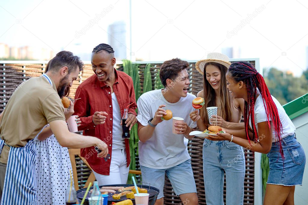 International Students eating burgers and drinking lemonade at barbecue patio party