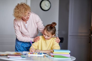 Yaratıcı aktivite. Mutlu yetişkin büyükanne ve küçük kız arkadaşlar masada otururlar.