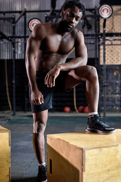 Ajuste sin camisa atlético africano hombre de pie junto a la caja de madera pliométrica en el gimnasio —  Fotos de Stock