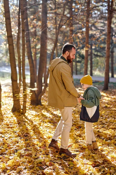 Bärtiger Mann, Vater, der mit seinem kleinen Sohn im Herbstpark im Wald spazieren geht. Familienkonzept — Stockfoto