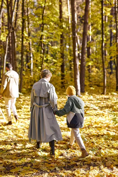 Bakifrån på ung kvinna promenader med barn pojke son, utomhus i parken — Stockfoto