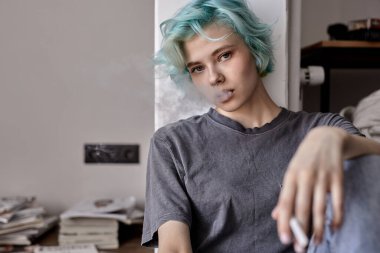 Bunalımlı kadın kendini yalnız ve üzgün hissediyor, evde oturmuş sigara içiyor.