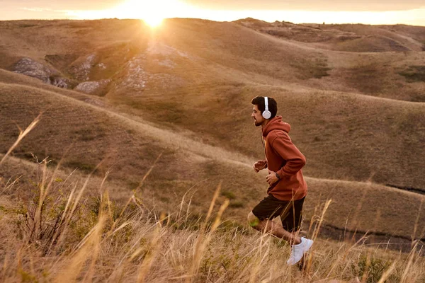Laufen männlich auf Sonnenuntergang feurigen Himmel Hintergrund in den Bergen, Sport und Erholung — Stockfoto
