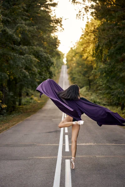 Jeune femme ballerine en body noir dansant sur pointe avec tissu violet — Photo