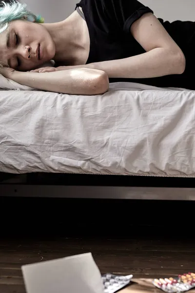 Przygnębiona kobieta leżąca na łóżku rozważająca popełnienie samobójstwa narkotykami i listem — Zdjęcie stockowe