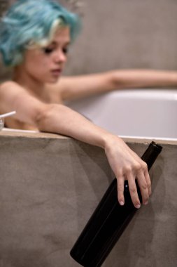 Mutsuz, ağlayan, küvette alkol içen, depresyon ve yalnızlık çeken bir kadın.