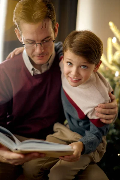 Весёлый семейный отец-одиночка, папа с сыном читают сказку отдых праздничный вечер в уютной комнате — стоковое фото
