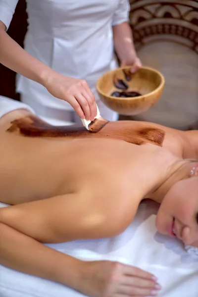 Massagem nas costas com máscara hidratante de chocolate. Processo de trabalho do massagista . — Fotografia de Stock