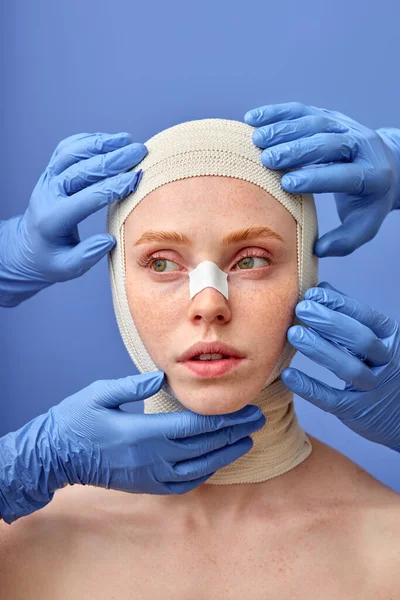 Egy fiatal nő a kozmetikai műtét után. Orvos kesztyűben Érintse meg a betegek arcát. — Stock Fotó