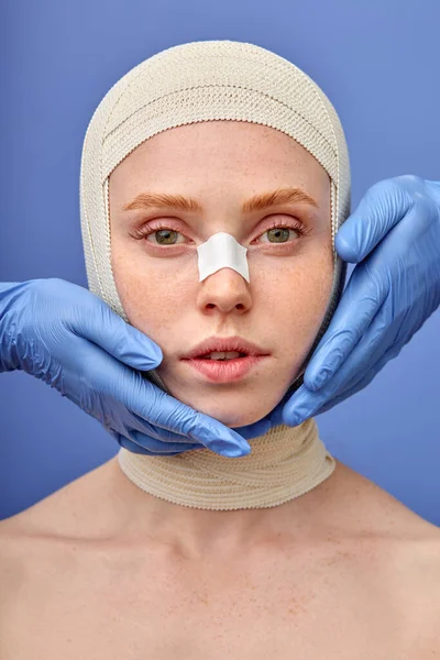 Nő néz kamera, megérintette orvos kesztyű, felkészülés a plasztikai sebészet — Stock Fotó