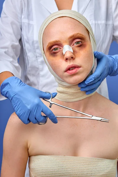 Después de la cirugía plástica. cosmetólogo recortado tocar mujer cara vusing instrumentos médicos — Foto de Stock