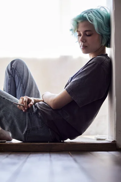 Nachdenkliche, nachdenkliche junge Frau sitzt auf dem Boden im Wohnzimmer und denkt nach — Stockfoto
