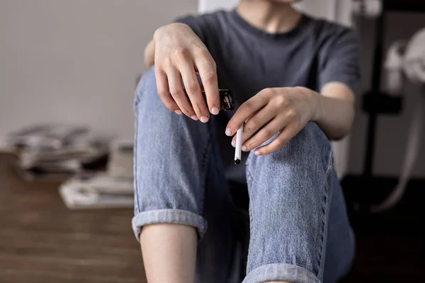 Ritagliato primo piano mani femminili che tengono la sigaretta in mano mentre seduto sul pavimento da solo — Foto Stock