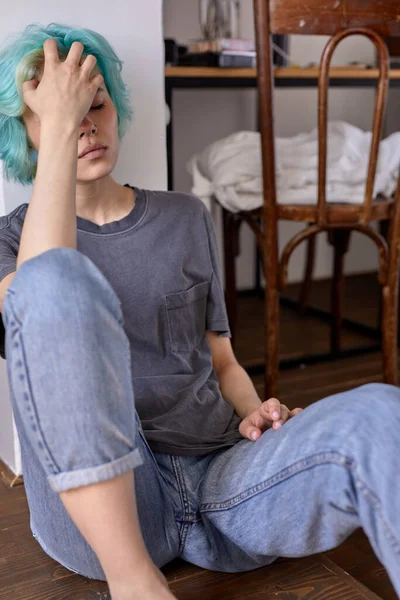 Przygnębiona młoda kobieta siedzi na podłodze w domu, myśląc o problemach i kłopotach — Zdjęcie stockowe