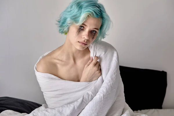Jovencita preocupada sentada en la cama envuelta en manta. Mujer estresada en casa —  Fotos de Stock