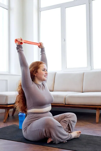 Aktif şişman kadın lastik bantlarla kol egzersizleri yapıyor, evde eğitim görüyor. — Stok fotoğraf