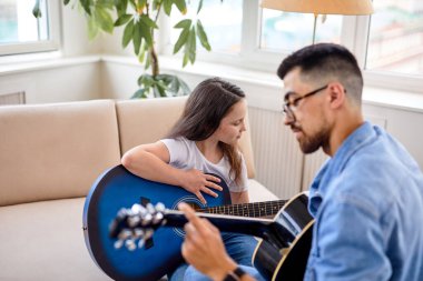 İyi bir adam ve küçük bir kız. Aile zamanı. Kanepede oturup gitar çalıyorlar.