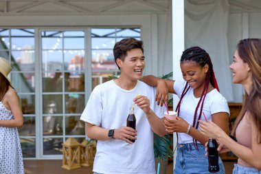 Güzel, mutlu, çeşitli arkadaşlar konuşuyor. Evin terasında eğleniyorlar.