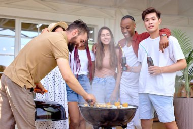 Gençler yaz akşamları barbekü yapıyor, çeşitli erkekler ve kadınlar.