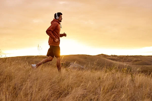 Laufen Mann bei Sonnenuntergang feurigen Himmel Hintergrund in den Bergen, Sport und Erholung — Stockfoto