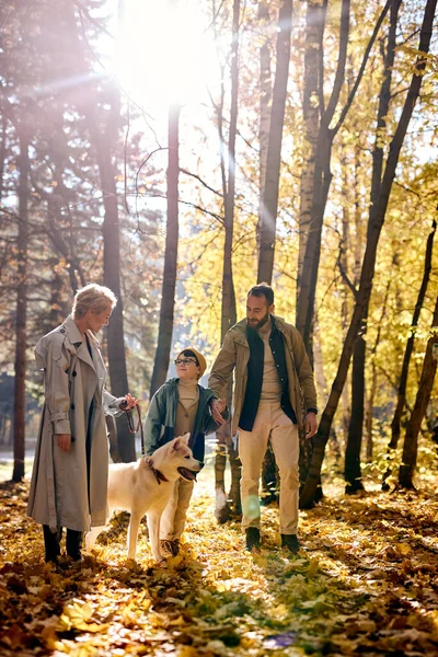 Glückliche Familie beim Spaziergang mit Sohn und weißem Haustier im Herbstwald. Familie, Freundschaft — Stockfoto