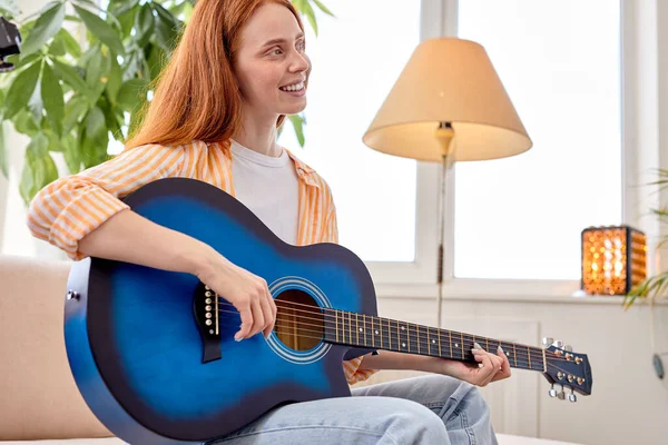 Portrait de jolie rousse femme dans l'usure occasionnelle jouer de la guitare, à la maison — Photo