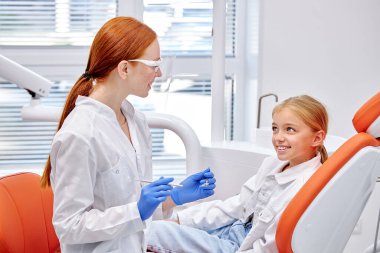 Modern diş hekimliğinde çocuk hastaların dişlerini muayene eden bir diş hekimi. Üniformalı doktor