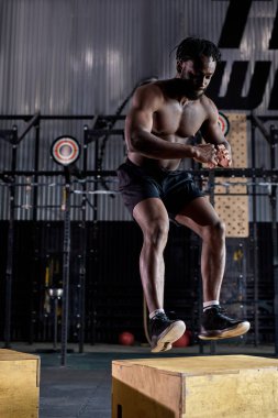 Aktif, güçlü, uyumlu, terli, iri kaslı, atlama egzersizi yapan bir afro adam.