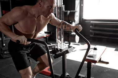 Beyaz tenli güçlü, fit terli, kaslı, kardiyo egzersizi yapan bir adam.