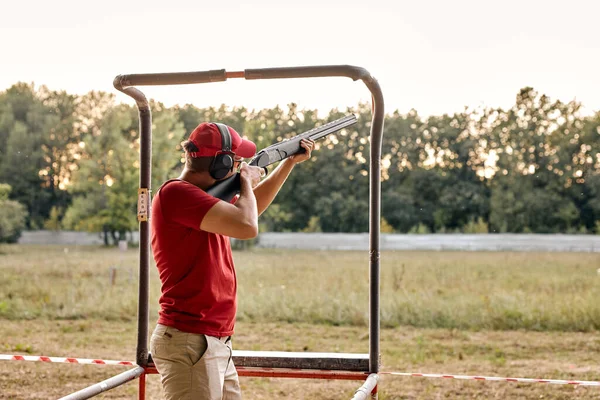 Jovem de óculos e fone de ouvido apontando rifle ao lado, pronto para atirar. — Fotografia de Stock