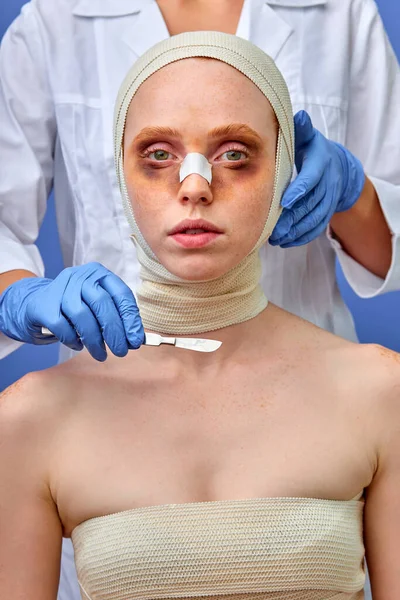 Après l'opération de chirurgie plastique. médecin toucher le visage de la femme en utilisant des instruments — Photo