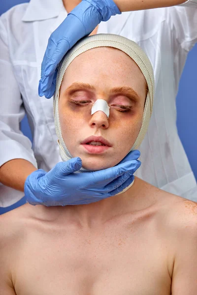Nő, kötéssel a feje fölött, orvos tapizás műtét után. elszigetelt kék háttér, stúdió lövés — Stock Fotó
