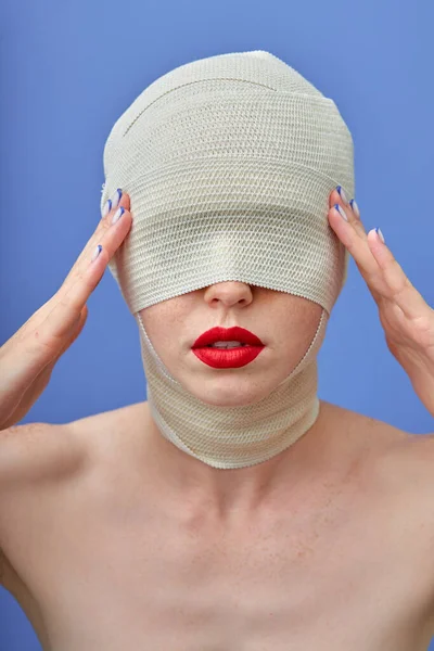 Oigenkännlig kvinna med stor röd läpp och med bandage i huvud och hals efter operation — Stockfoto