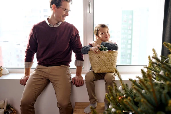 Papá joven se sienta con el niño en casa cerca del árbol de Navidad, hablando, descansando. — Foto de Stock