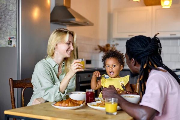 Νεαρή οικογένεια με παιδί που παίρνει πρωινό στο σπίτι. Ευτυχισμένες οικογενειακές στιγμές τρόπου ζωής. — Φωτογραφία Αρχείου