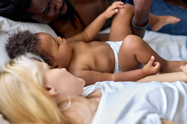 Impresionante niño negro acostado en la cama con los padres, Descansando juntos. En casa — Foto de Stock