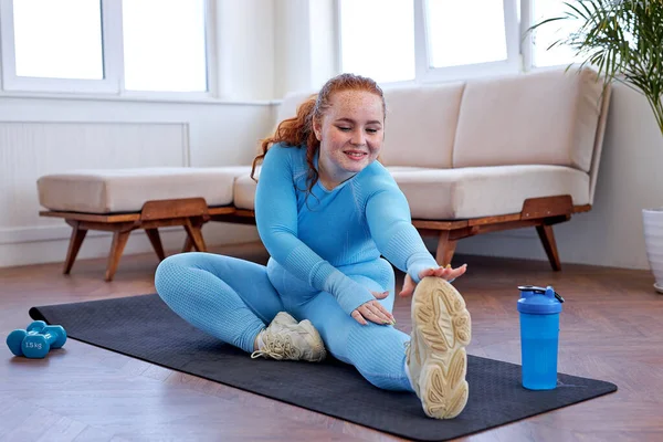 Kafkasyalı kadın bacak esnetiyor, yoga minderinde egzersiz yapıyor, aktif bir hayat sürüyor. — Stok fotoğraf