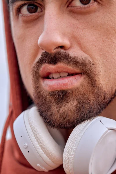 Foto de close-up do rosto masculino, lábios, barba e olhos, usando fones de ouvido — Fotografia de Stock