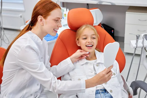 Redhead kvinnlig tandläkare i uniform arbetar med barn patient i tandläkarmottagningen — Stockfoto