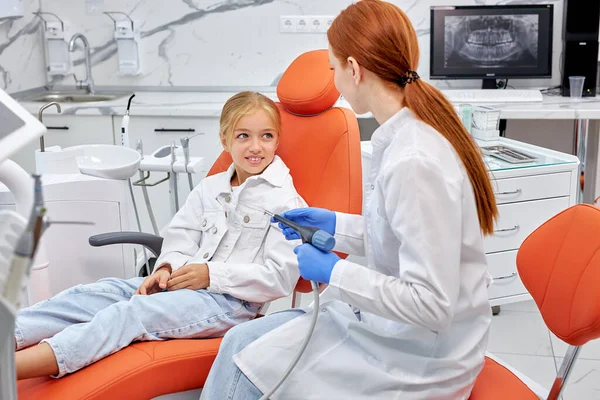 Professionell kvinnlig tandläkare kommunicera med söta barn patient samtidigt kontrollera tänder — Stockfoto
