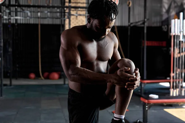Motivado deportista negro sano calentando los músculos de las piernas, estirándose antes del entrenamiento —  Fotos de Stock