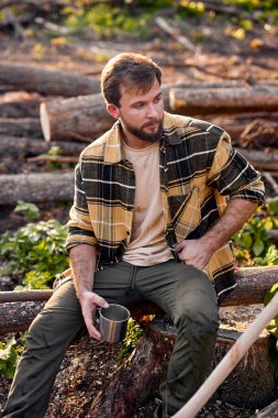 Yakışıklı adam, ağaç kestikten sonra çay içip dinleniyor.