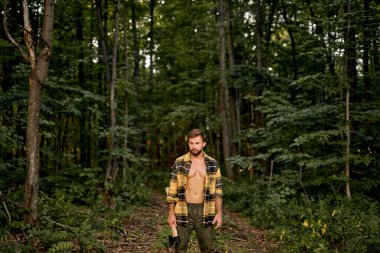 Ağaç kesme mevsimi. Kendine güvenen keresteci ormanda balta taşıyor. Orman odunculuğu.