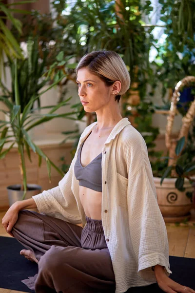 Kendinden emin beyaz kadın mindere oturmuş yoga meditasyonu yapacak. — Stok fotoğraf