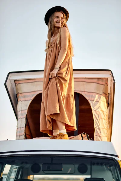 Emocionado encantadora dama está en el techo de mini furgoneta amarilla, disfrutar de la puesta de sol desde la parte superior —  Fotos de Stock