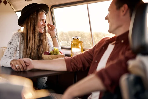 Веселая взволнованная пара путешествует вместе, держа друг друга за руки, сидя в фургоне — стоковое фото