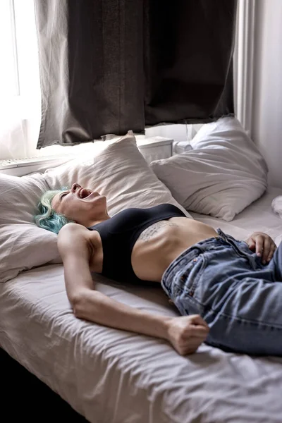 En deprimerad ung kvinna som ligger i sängen. Psykiska problem med depression och bulimi. — Stockfoto